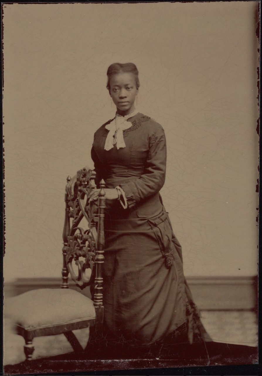 Full length portrait; young lady standing by chair, white neck piece