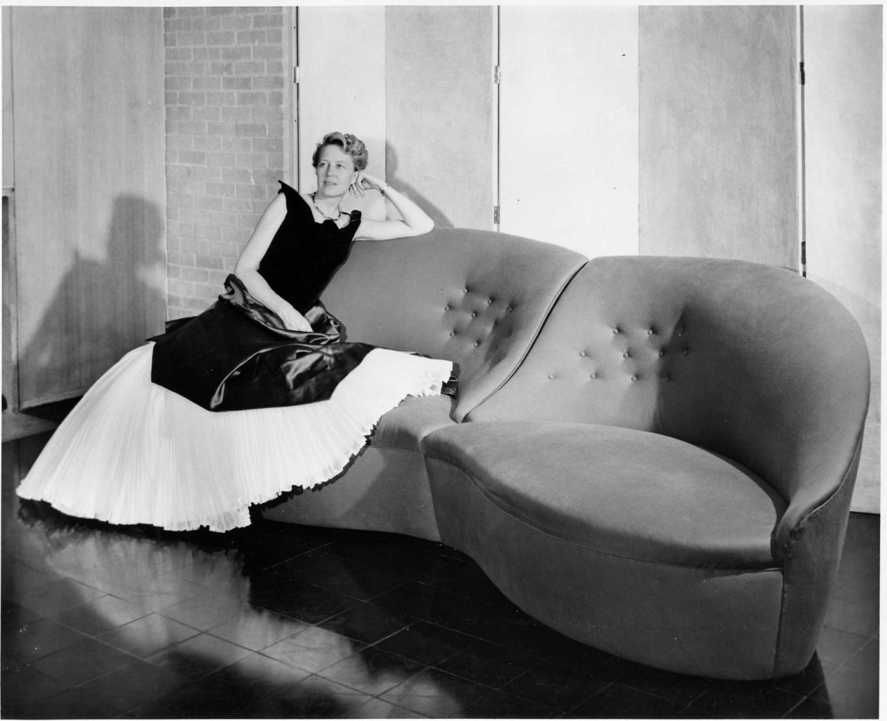 Dominique de Menil in a Charles James gown seated on a sofa of his design