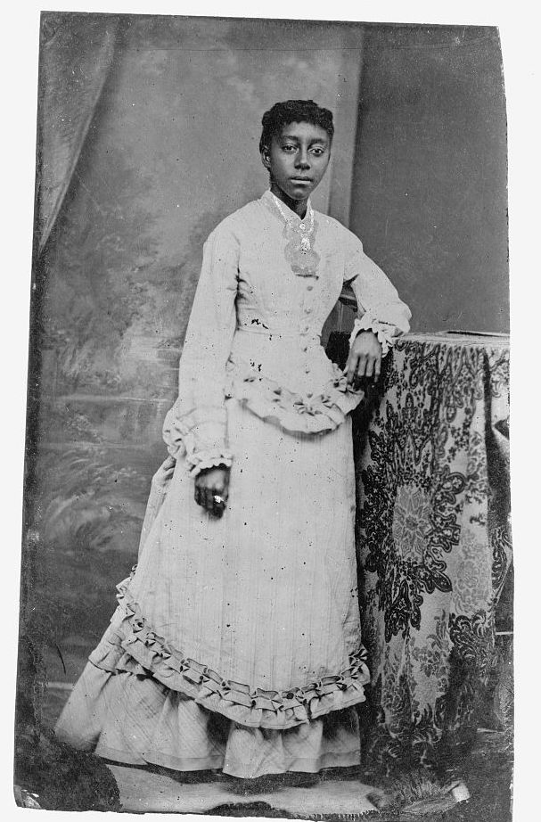 Young African American woman, standing with one arm resting on a table